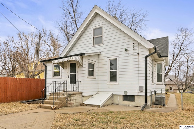 view of front facade with central AC, a patio, roof with shingles, and fence