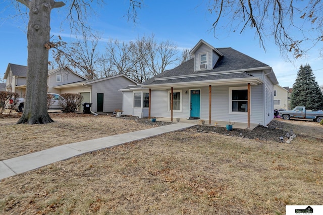 view of front of property featuring a shingled roof, a front yard, and covered porch