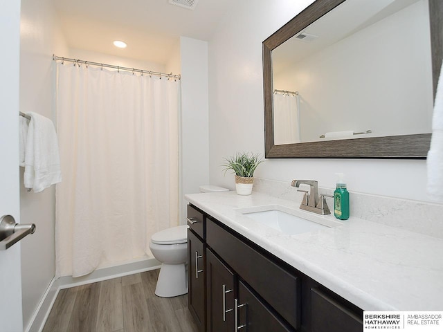 bathroom featuring toilet, visible vents, wood finished floors, and vanity