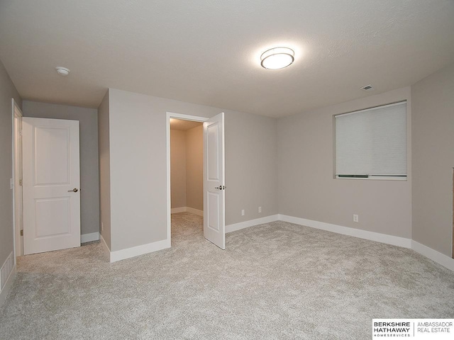 unfurnished bedroom with light carpet, a textured ceiling, visible vents, and baseboards