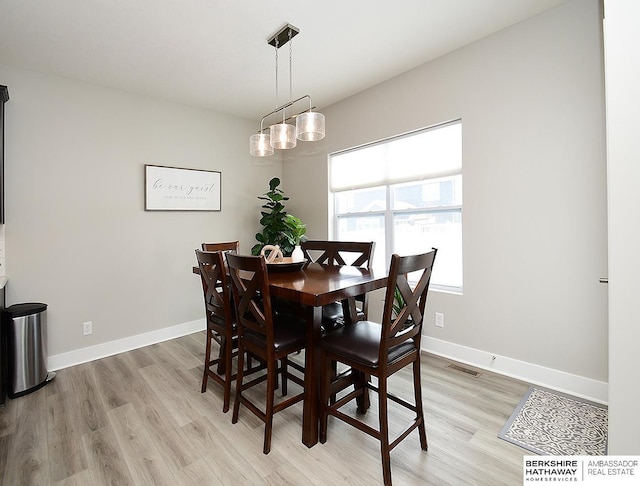 dining space featuring light wood-style floors, visible vents, and baseboards