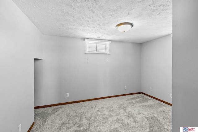 carpeted empty room featuring a textured ceiling, visible vents, and baseboards