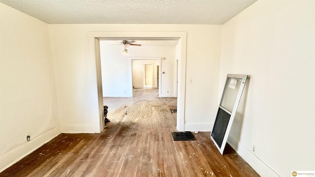 interior space with a textured ceiling, dark wood-style flooring, and baseboards