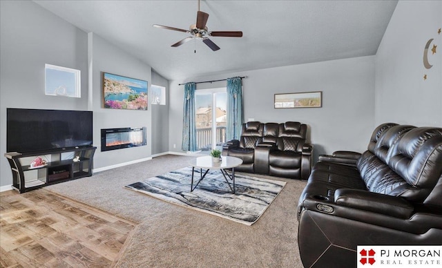 living room featuring carpet, lofted ceiling, a glass covered fireplace, ceiling fan, and baseboards