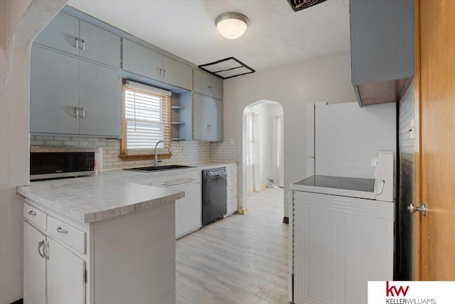 kitchen with arched walkways, black dishwasher, light countertops, stainless steel microwave, and a sink