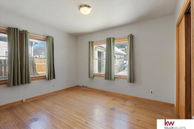 spare room with baseboards, visible vents, and light wood-style floors