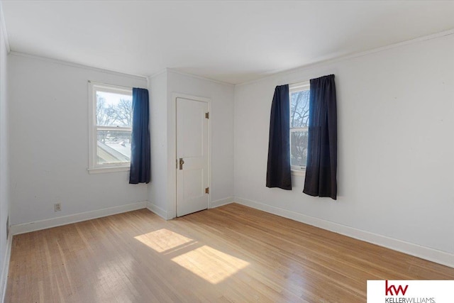 empty room with baseboards, a healthy amount of sunlight, and light wood finished floors