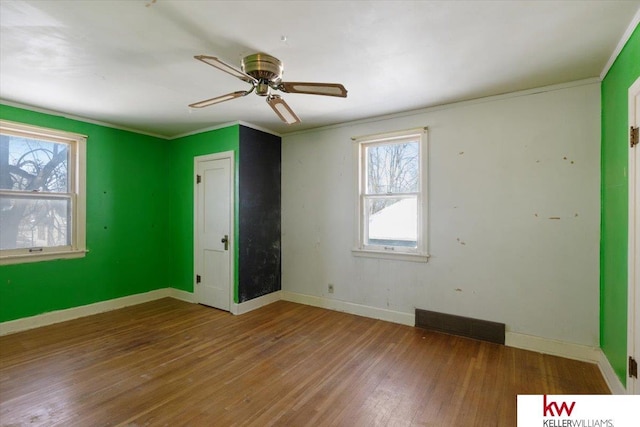 unfurnished bedroom featuring ornamental molding, visible vents, baseboards, and wood finished floors