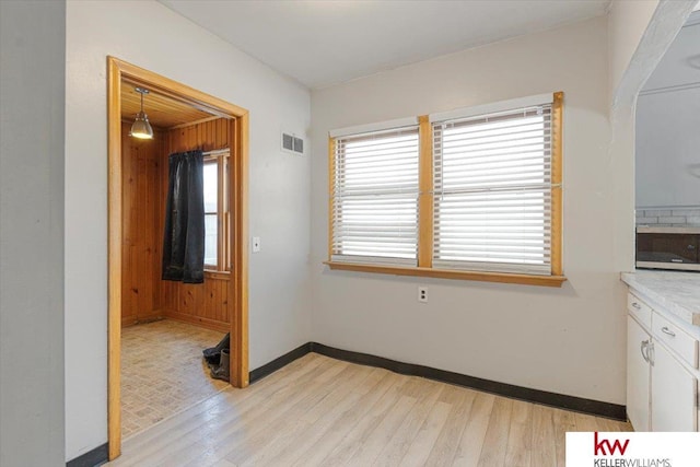 unfurnished dining area featuring light wood-style floors, visible vents, and baseboards