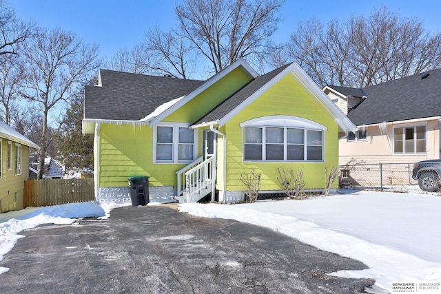 bungalow-style home featuring a shingled roof, entry steps, and fence