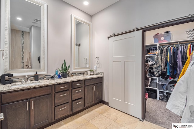 bathroom featuring tile patterned flooring, a sink, a spacious closet, and double vanity