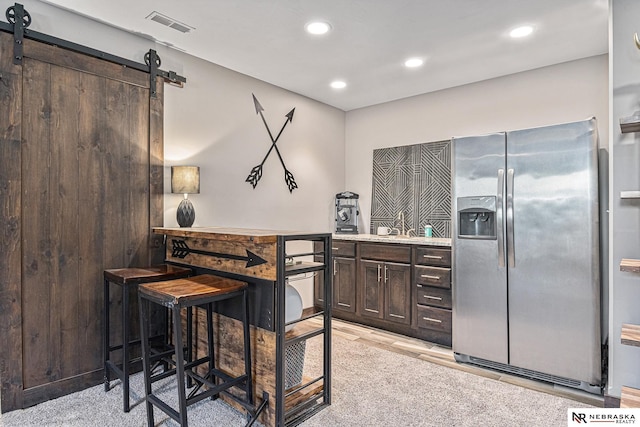 interior space featuring light countertops, visible vents, stainless steel fridge with ice dispenser, and a barn door