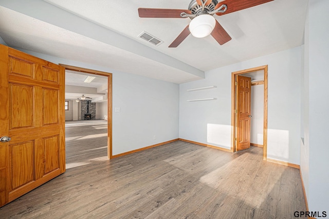 unfurnished room with ceiling fan, light wood-style flooring, visible vents, and baseboards