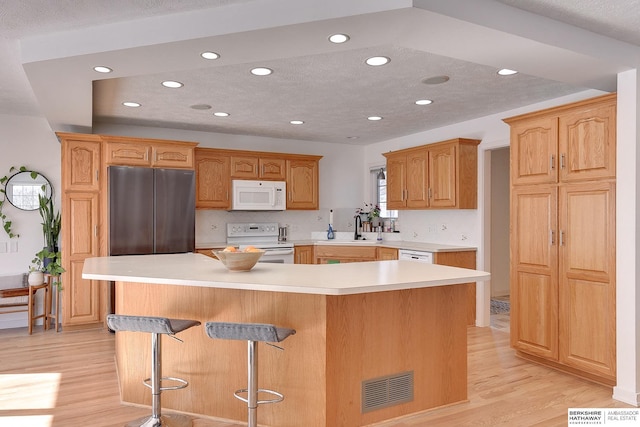 kitchen with light countertops, white appliances, visible vents, and a center island