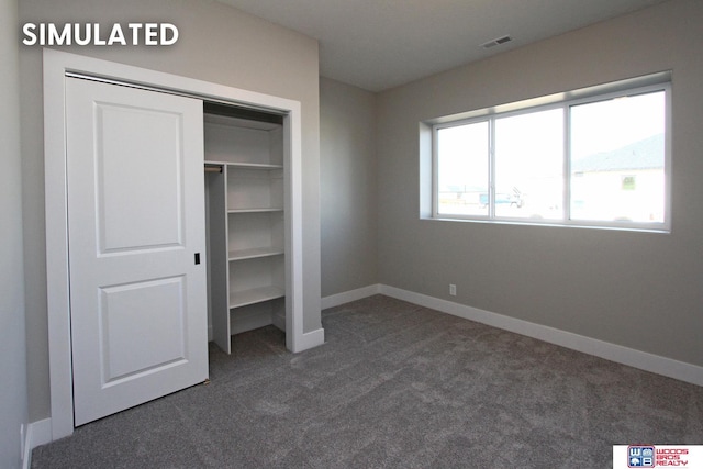 unfurnished bedroom with baseboards, visible vents, dark carpet, and a closet