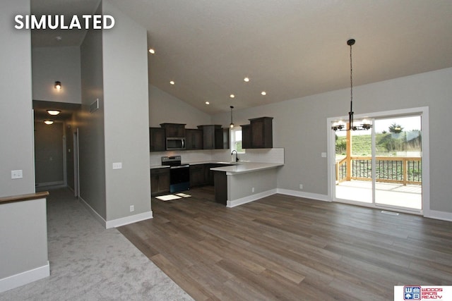 kitchen featuring light countertops, stainless steel microwave, open floor plan, range with electric cooktop, and a peninsula