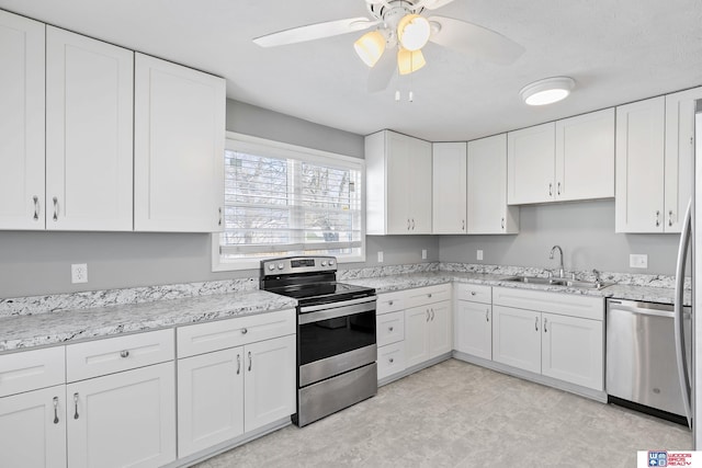 kitchen with light stone countertops, white cabinetry, stainless steel appliances, and a sink