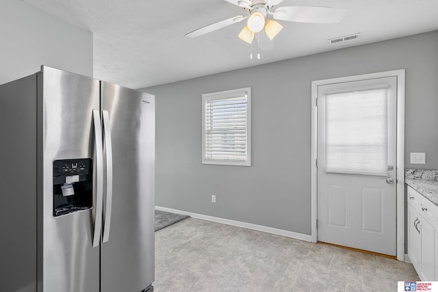 kitchen featuring stainless steel fridge with ice dispenser, light countertops, a ceiling fan, white cabinets, and baseboards