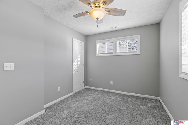 carpeted spare room featuring a ceiling fan, visible vents, a textured ceiling, and baseboards