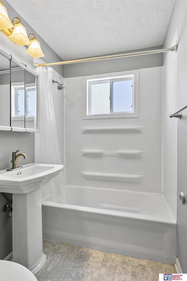 bathroom with a textured ceiling and shower / bathtub combination with curtain