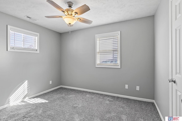 carpeted spare room featuring a ceiling fan, visible vents, a textured ceiling, and baseboards