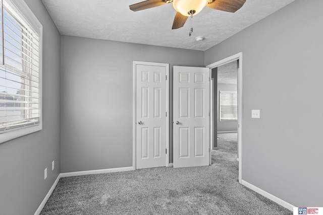 unfurnished bedroom with carpet, ceiling fan, a textured ceiling, and baseboards