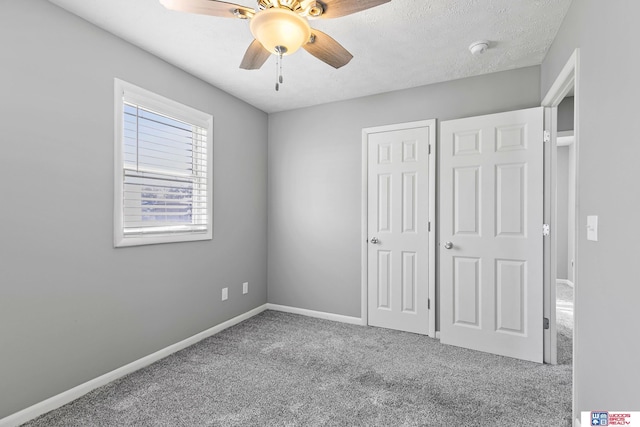 unfurnished bedroom featuring a closet, carpet flooring, ceiling fan, a textured ceiling, and baseboards