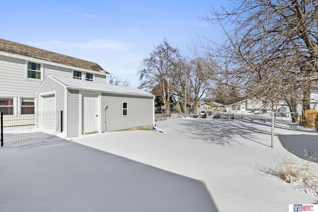 snow covered property with a garage and fence