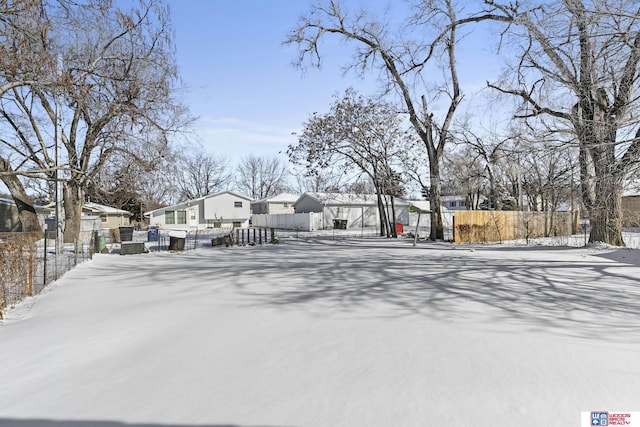 snowy yard featuring fence and a residential view