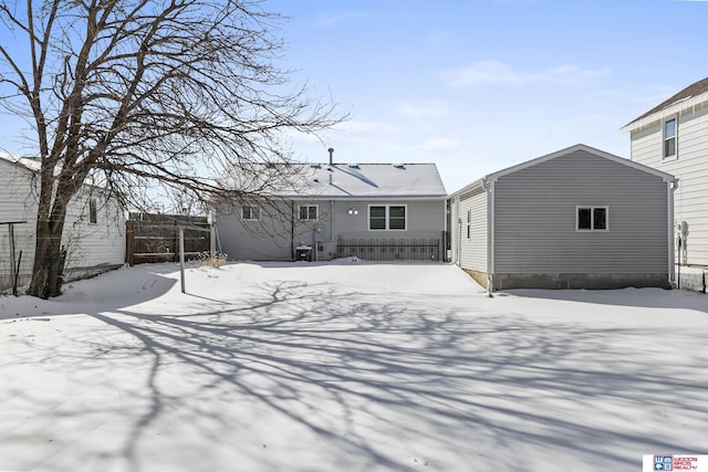 snow covered back of property featuring fence