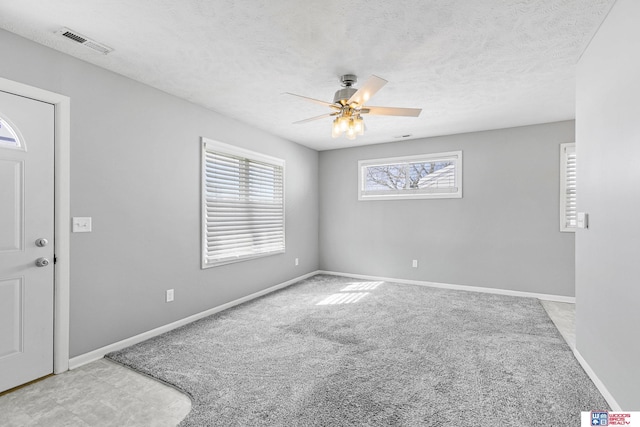 empty room with a ceiling fan, visible vents, a textured ceiling, and baseboards