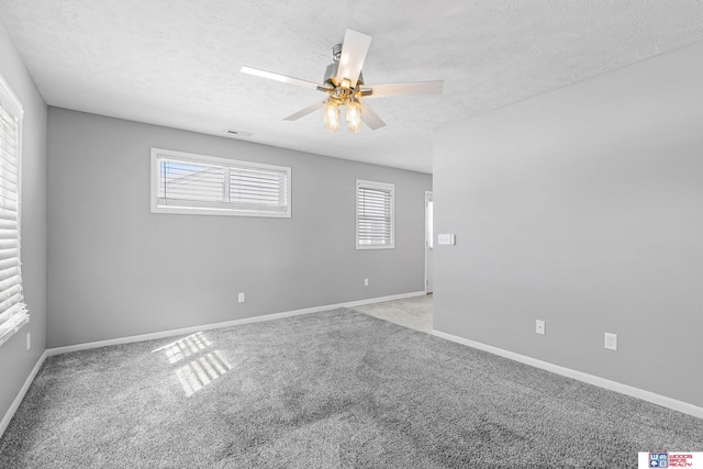 empty room with a ceiling fan, light colored carpet, a textured ceiling, and baseboards