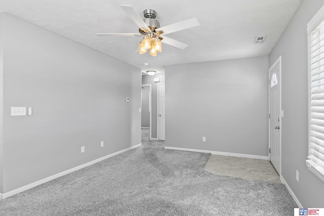 unfurnished room featuring a textured ceiling, carpet floors, visible vents, a ceiling fan, and baseboards