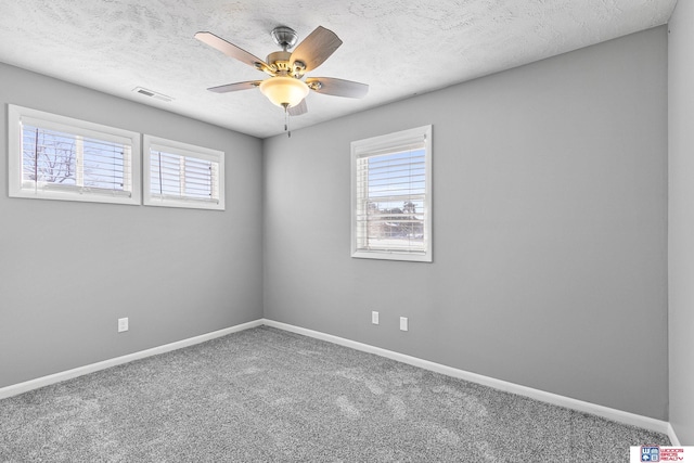 spare room featuring baseboards, carpet, visible vents, and a wealth of natural light