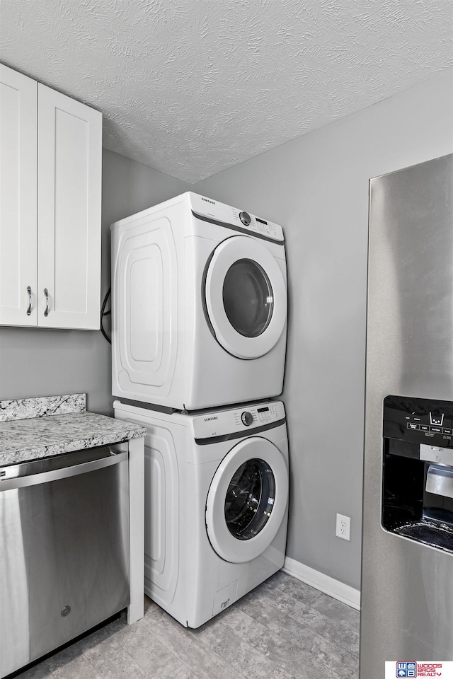 laundry room featuring laundry area, baseboards, a textured ceiling, and stacked washer and clothes dryer