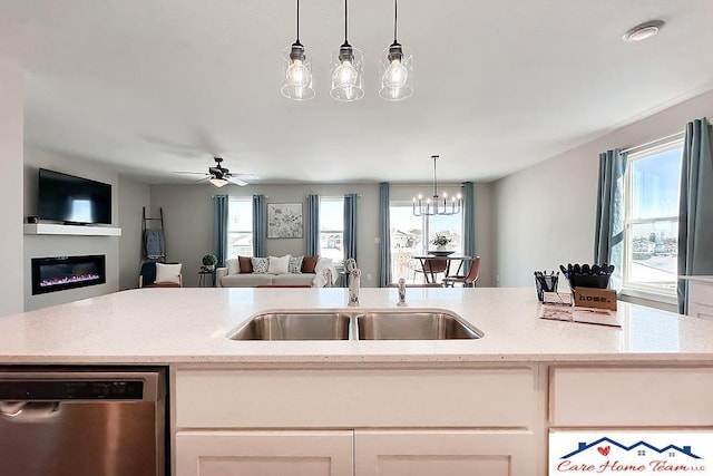 kitchen with a sink, open floor plan, stainless steel dishwasher, and hanging light fixtures