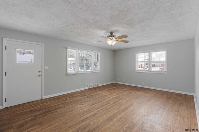 interior space featuring baseboards, wood finished floors, visible vents, and a healthy amount of sunlight