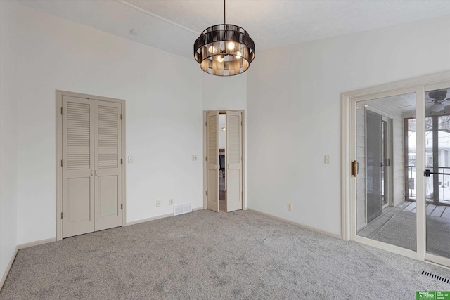 spare room with a chandelier, carpet, visible vents, and baseboards