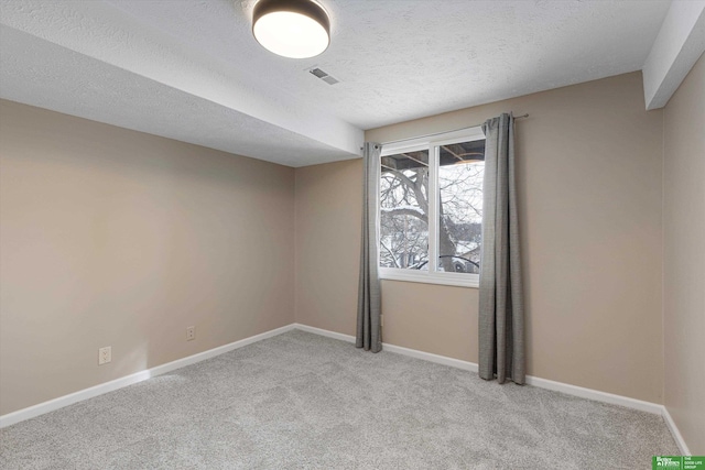 empty room with visible vents, light carpet, baseboards, and a textured ceiling