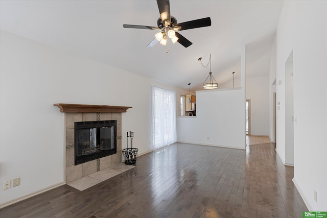 unfurnished living room with lofted ceiling, a tiled fireplace, ceiling fan, wood finished floors, and baseboards