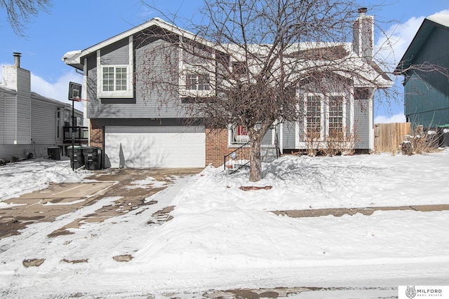 view of front facade featuring a garage, brick siding, fence, and central air condition unit