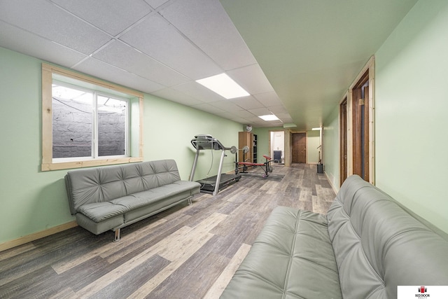 living room featuring a paneled ceiling, baseboards, and wood finished floors