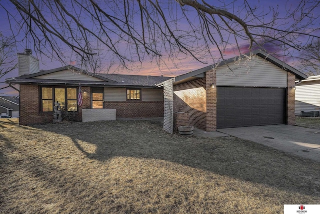 view of front of house with a garage, driveway, a chimney, a front lawn, and brick siding