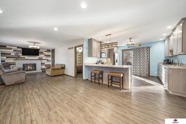 living room featuring a glass covered fireplace, visible vents, recessed lighting, and wood finished floors