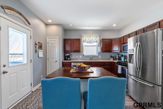 kitchen featuring dark countertops, appliances with stainless steel finishes, a center island, a sink, and recessed lighting