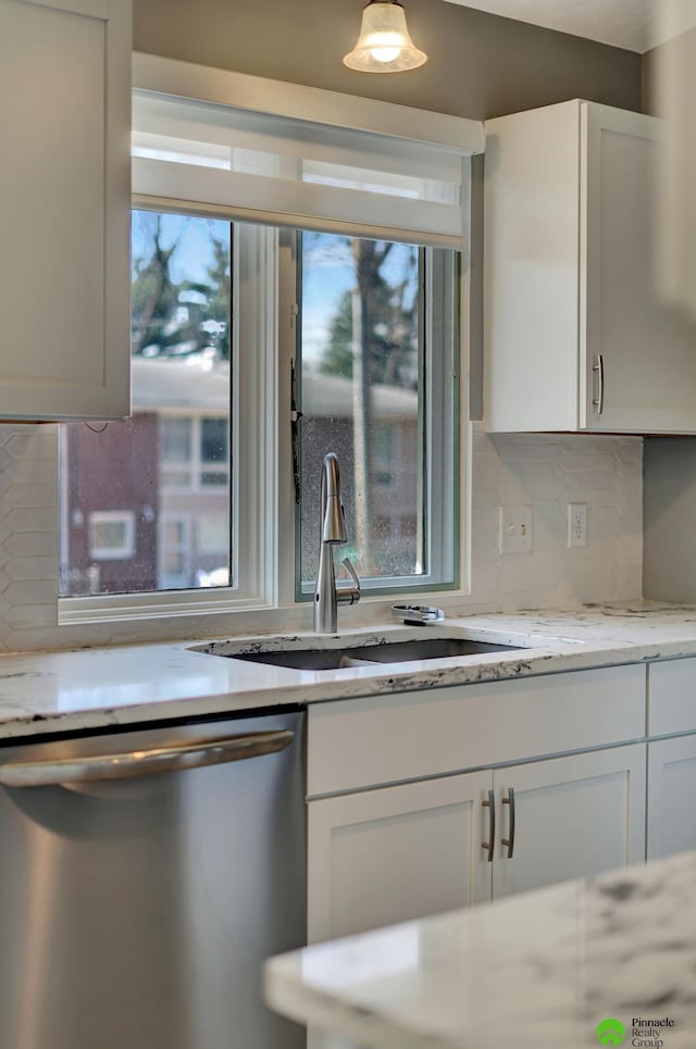 kitchen featuring dishwasher, decorative backsplash, white cabinetry, and a sink