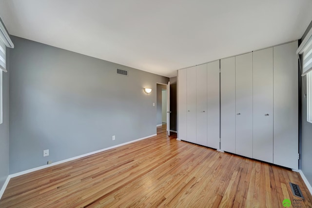 unfurnished bedroom featuring light wood-style flooring, baseboards, and visible vents