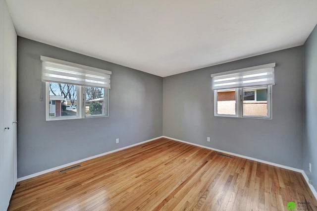 spare room featuring wood finished floors, visible vents, and baseboards