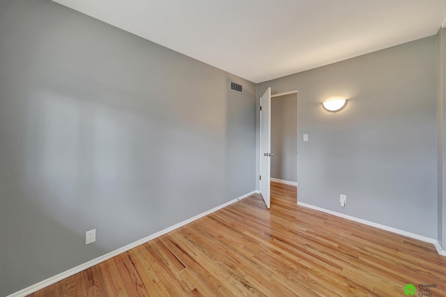 empty room with visible vents, light wood-type flooring, and baseboards