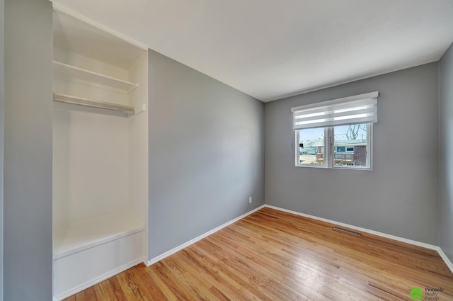 unfurnished bedroom featuring visible vents, wood finished floors, and baseboards